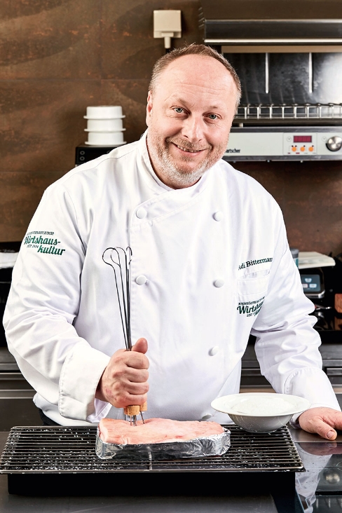 Haubenkoch Adi Bittermann beim Grill stehend